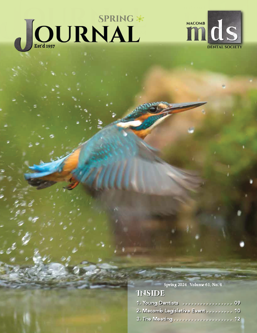 Cover of Journal of Macomb Dental Society with a small blue and orange bird taking flight from a pool of water with droplets of water splashing around it.