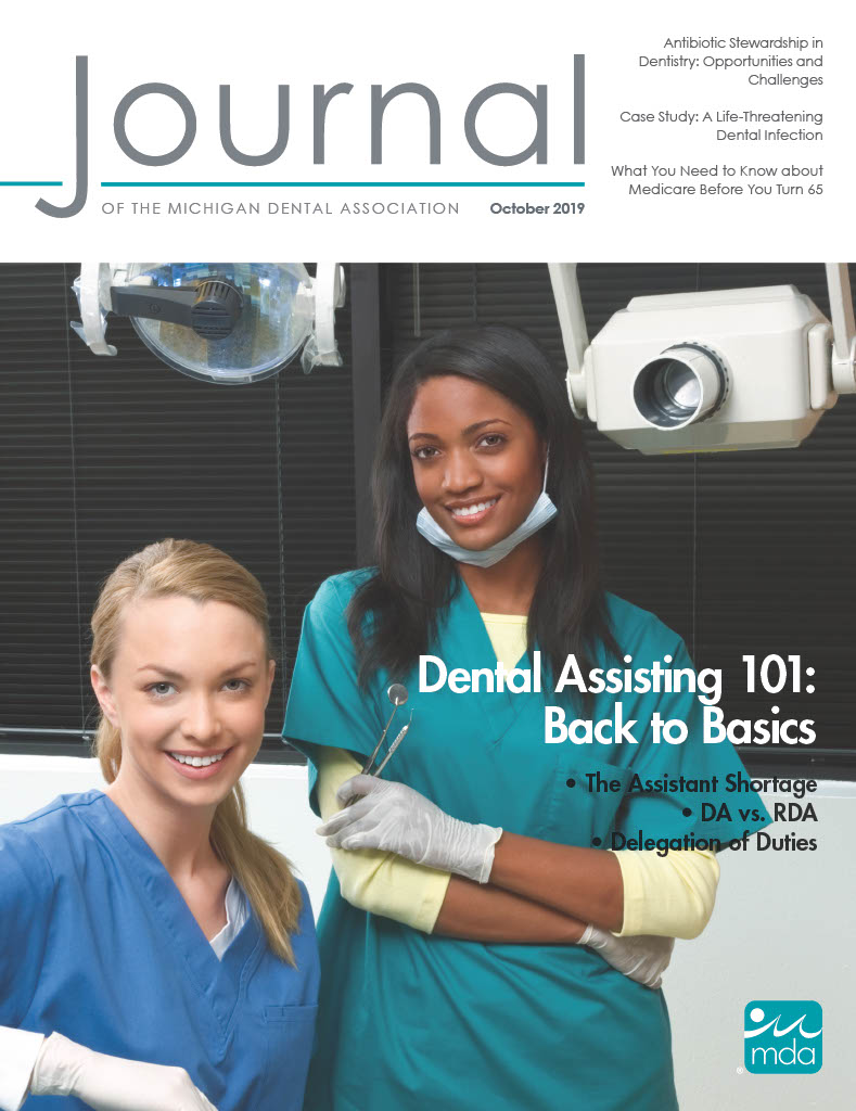 Cover of the Journal of the Michigan Dental Association with two people looking at the viewer in a dental office. Both have nitrile gloves; one is sitting casually in light blue scrubs and the other is standing wearing teal scrubs and a face mask pulled down, holding dental cleaning tools.